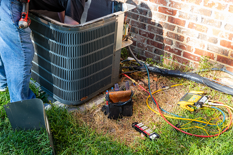 3 Tips to Prevent AC Breakdown During a Heat Wave. Photo of an air conditioner maintenance being performed.
