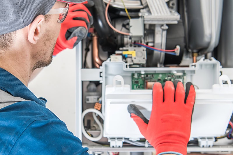 4 Signs Your Furnace Needs Repair Before It Breaks Down. Heating Central Gas Furnace Issue. Technician Trying To Fix the Problem with the Residential Heating Equipment.